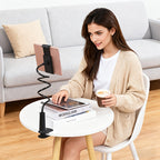 Black flexible hose tablet holder with clamp base, 360° adjustable, used by a woman at a white table.